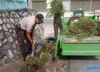 Bhabinkamtibmas Polsek Balai Karimun, AIPTU Waluyo Hambali saat membersihkan selokan