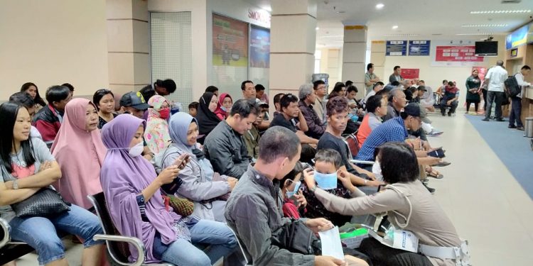 Anggota Dirlantas Kepri saat memasangkan masker kepada masyarakat di kantor Samsat Kepri