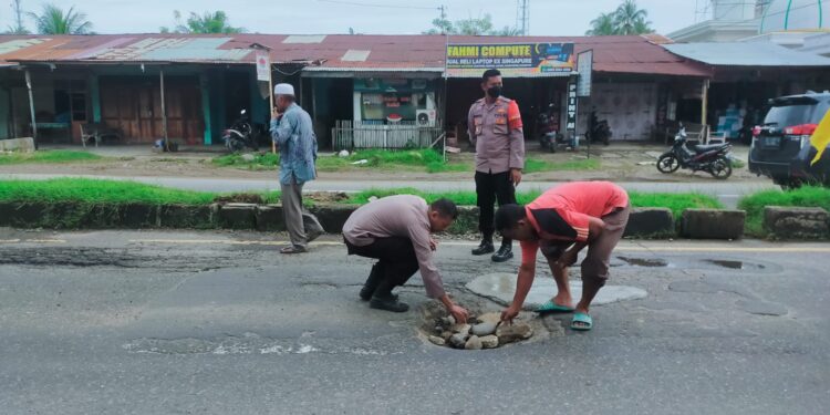 Beri Rasa Aman Bagi Pengendara, Personel Polsek Muara Satu Bersama Warga Tambal Jalan Berlubang